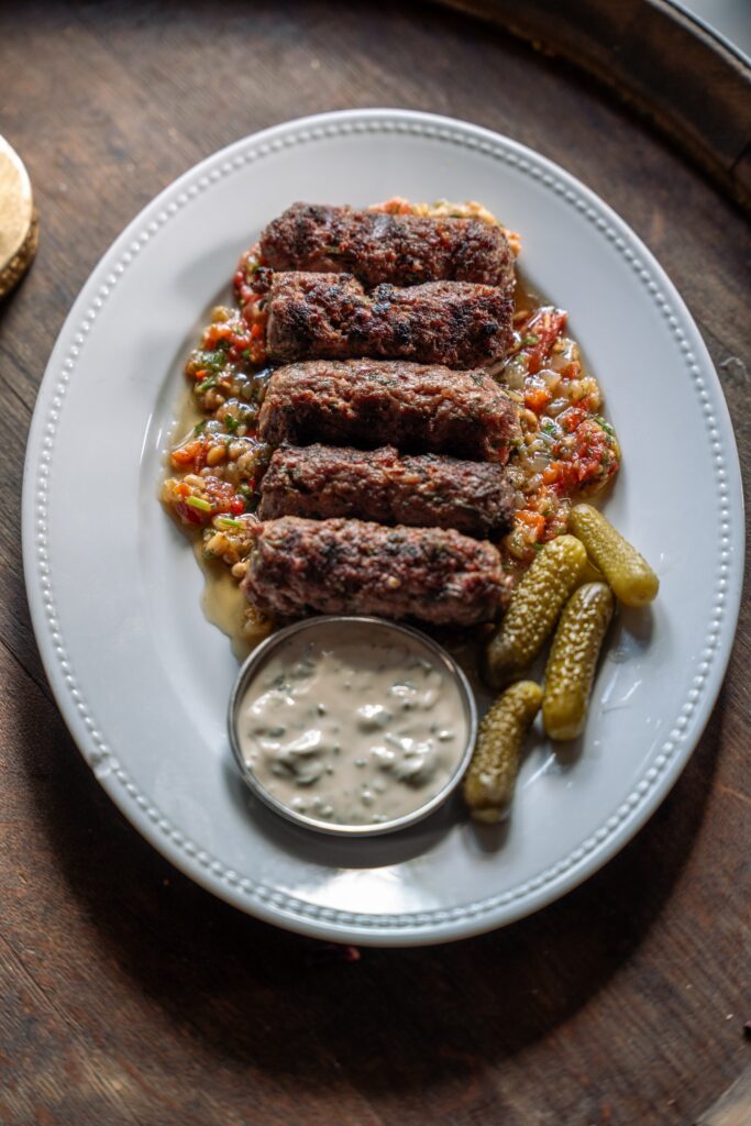 קבבים צלויים בצלחת עם חמוצים ורוטב